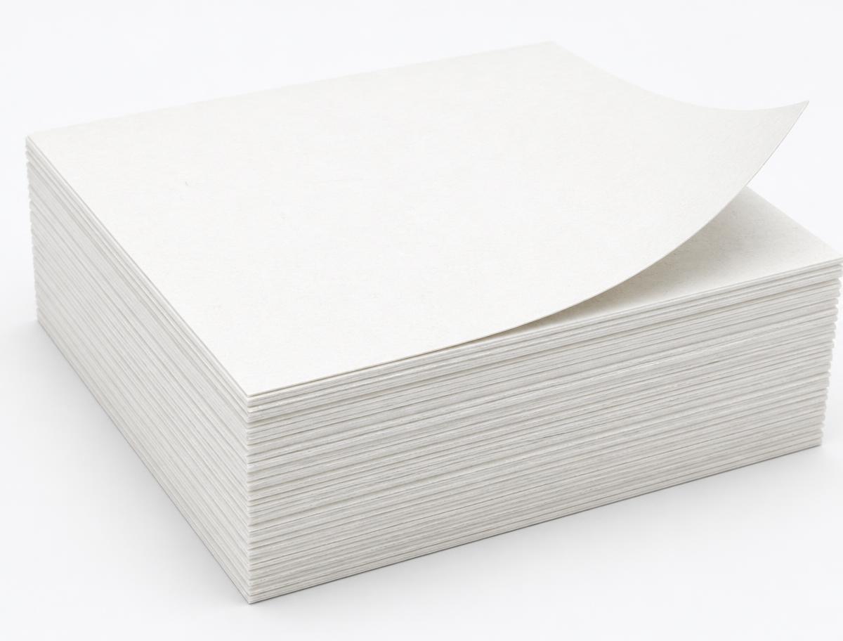 Neat stack of bright white bleached hardwood kraft market pulp sheets with one corner lifted