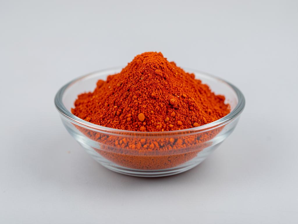 Cayenne Pepper Powder shown as a milled spice powder in a shallow dish in a neutral studio photograph
