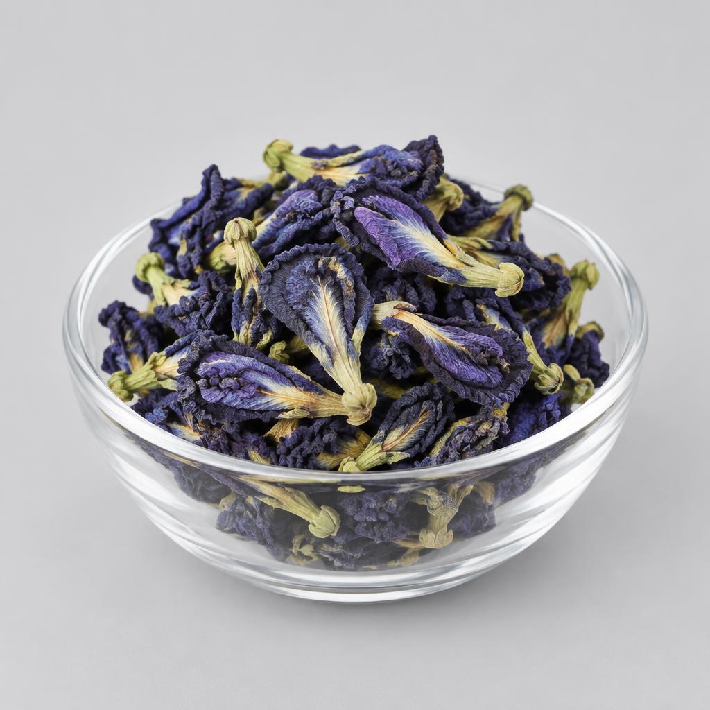 Dried Butterfly Pea Flowers — studio photograph of whole dried blue-violet Clitoria ternatea flowers with papery curled petals in a glass dish