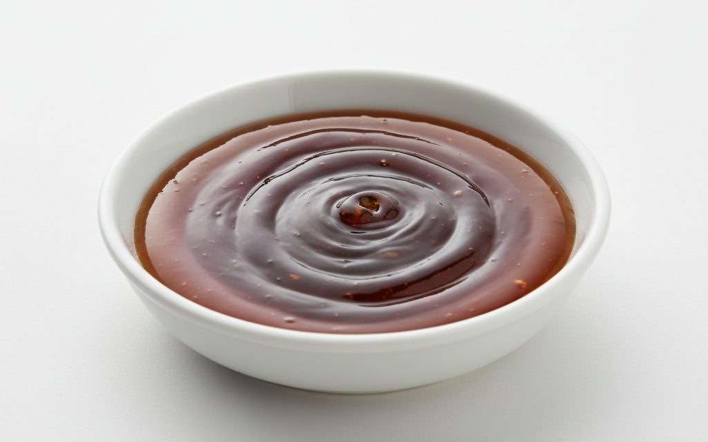 Grade confirmed at quotation — thick, viscous dark amber to brown translucent liquid with a heavy, tacky feel and a strong sulfurous mineral scent, studio product photograph