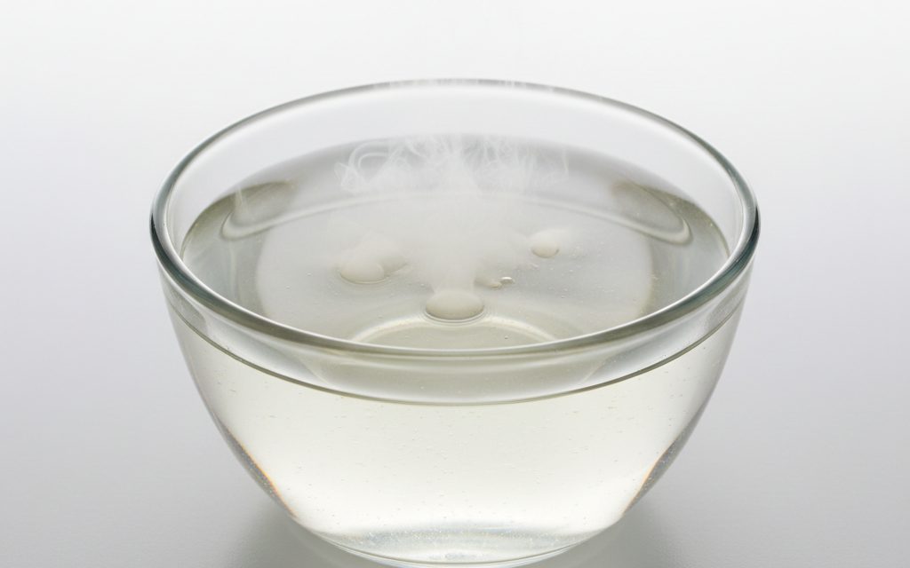 Grade confirmed at quotation — clear, colorless to slightly yellowish pungent liquid; fumes visibly in moist air and has a sharp, stinging odor, studio product photograph