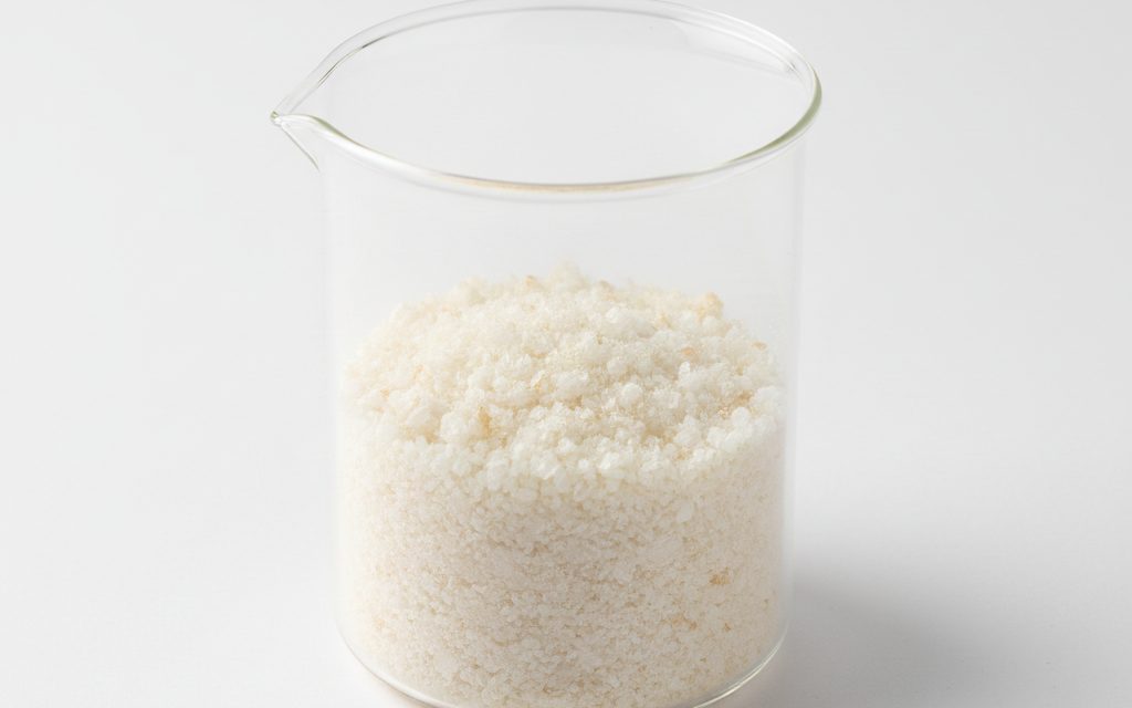 Grade confirmed at quotation — off-white to pale yellow crystalline powder, slightly tan tint possible, exhibiting a dry and relatively dense particle structure, studio product photograph