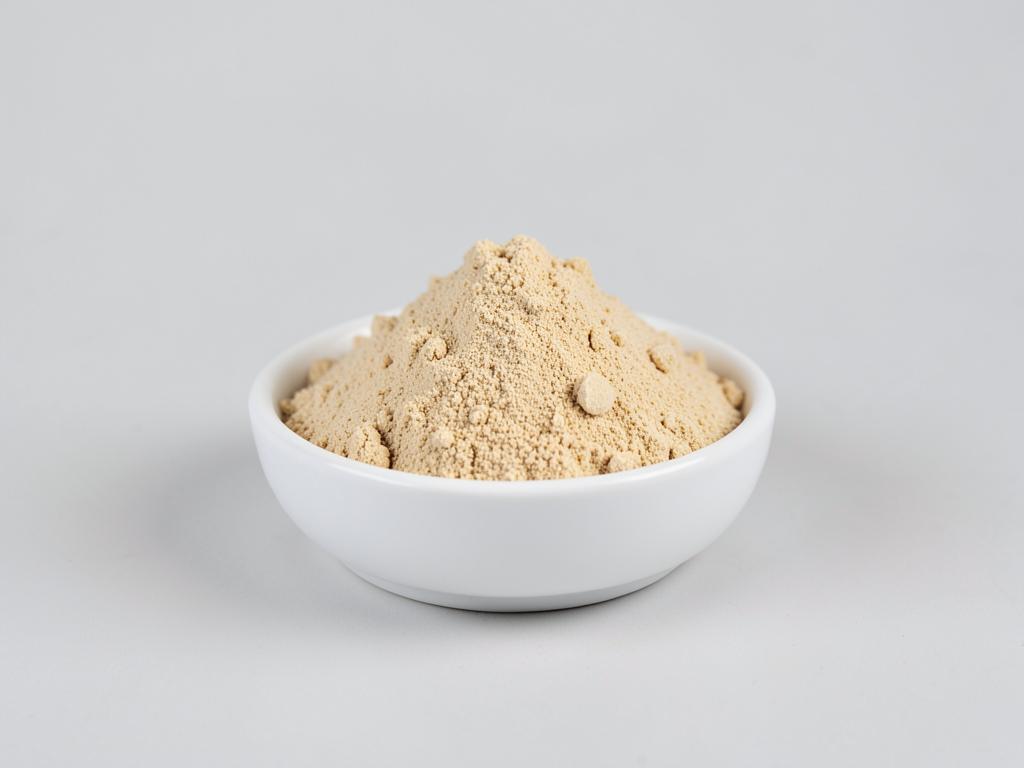 Malted milk powder shown as a light tan free-flowing powder heap in a neutral studio photograph