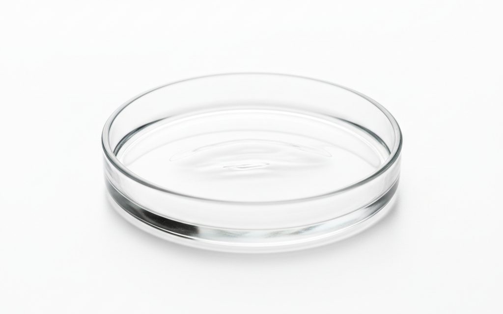 Grade confirmed at quotation — a transparent, colorless, oily liquid that is completely odorless and tasteless with high optical clarity, studio product photograph