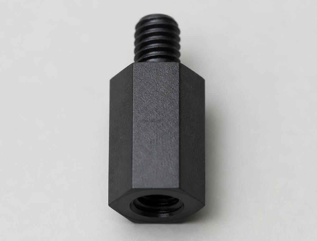 Macro view of a single black nylon hex standoff showing the female thread at one end and the male threaded stud at the other