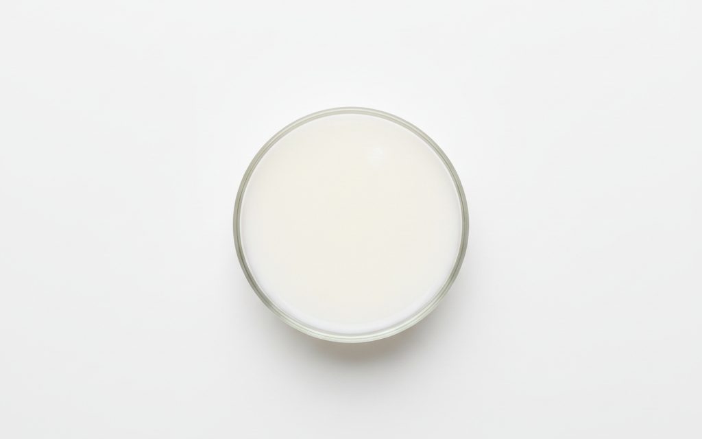 Grade confirmed at quotation — a milky white, opaque liquid with a water-like to slightly creamy consistency and mild chemical scent, studio product photograph