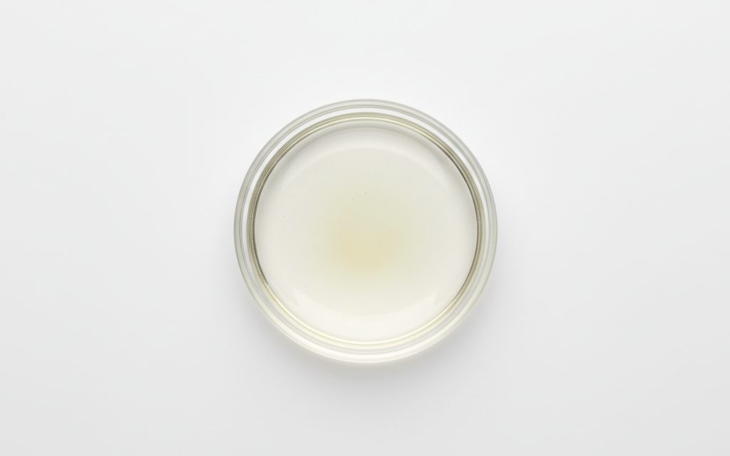 Grade confirmed at quotation — clear, colorless to pale yellow viscous liquid with a slight ammoniacal odor, darkening slightly upon exposure to light, studio product photograph